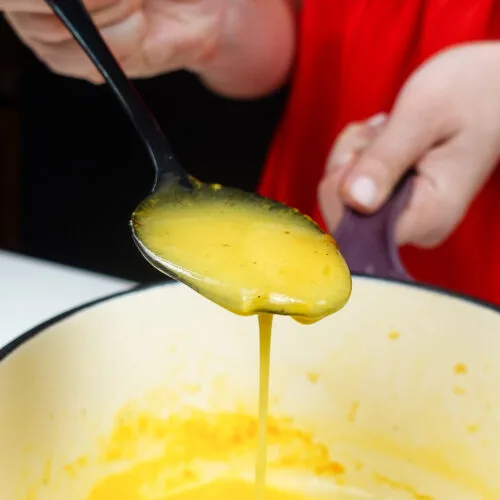 A closeup of one spoon of Beurre Blanc Sauce with Saffron in Helena's hands