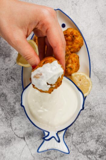 Garlic Yogurt Sauce with one shrimp croquette in one hand