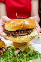 Helena is holding octopus burger in two hands