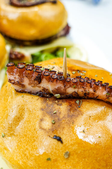 A closeup of octopus tentacle on top of burger