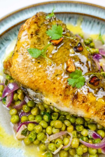 A closeup of beautiful sea bream with sauce and peas