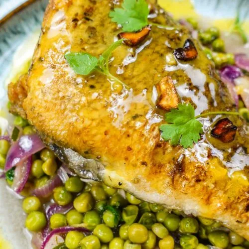A closeup of beautiful sea bream with sauce and peas