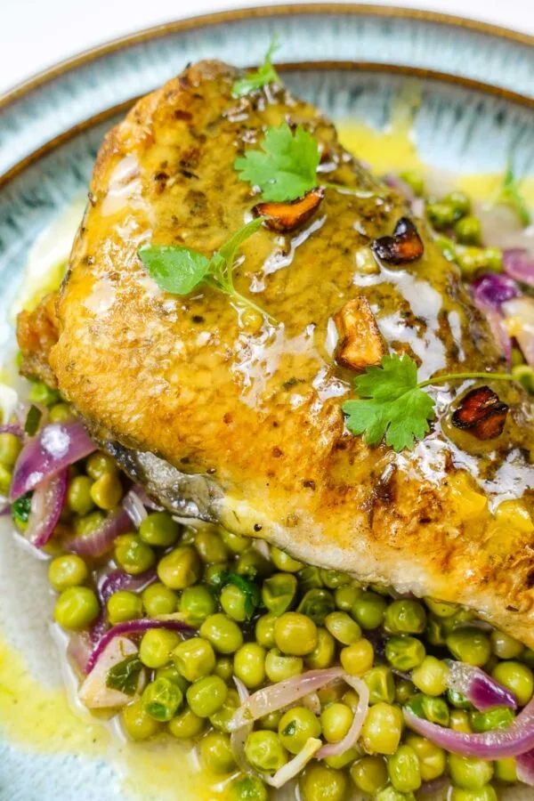 A closeup of beautiful sea bream with sauce and peas
