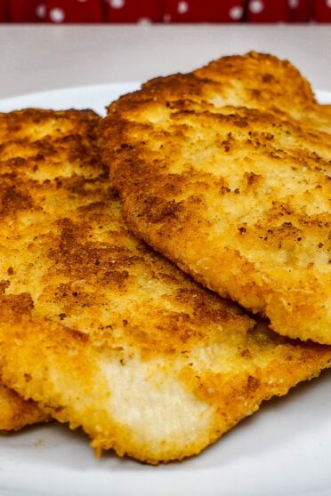 A plate with golden fried juicy turkey cutlets on a white plate