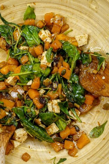A big bowl of pumpkin feta cheese salad with raisins and almond petals
