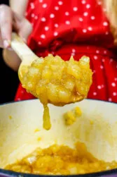 Helena is holding a spoon with a ready golden pear jam over the pot