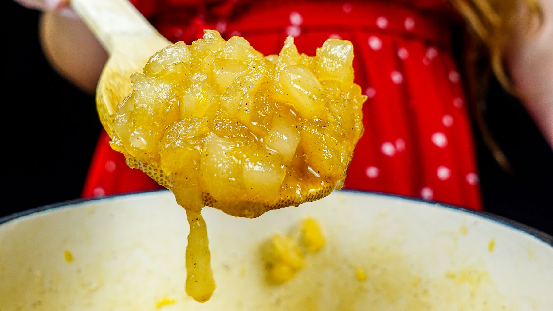 Helena is holding a spoon of pear jam over the pot