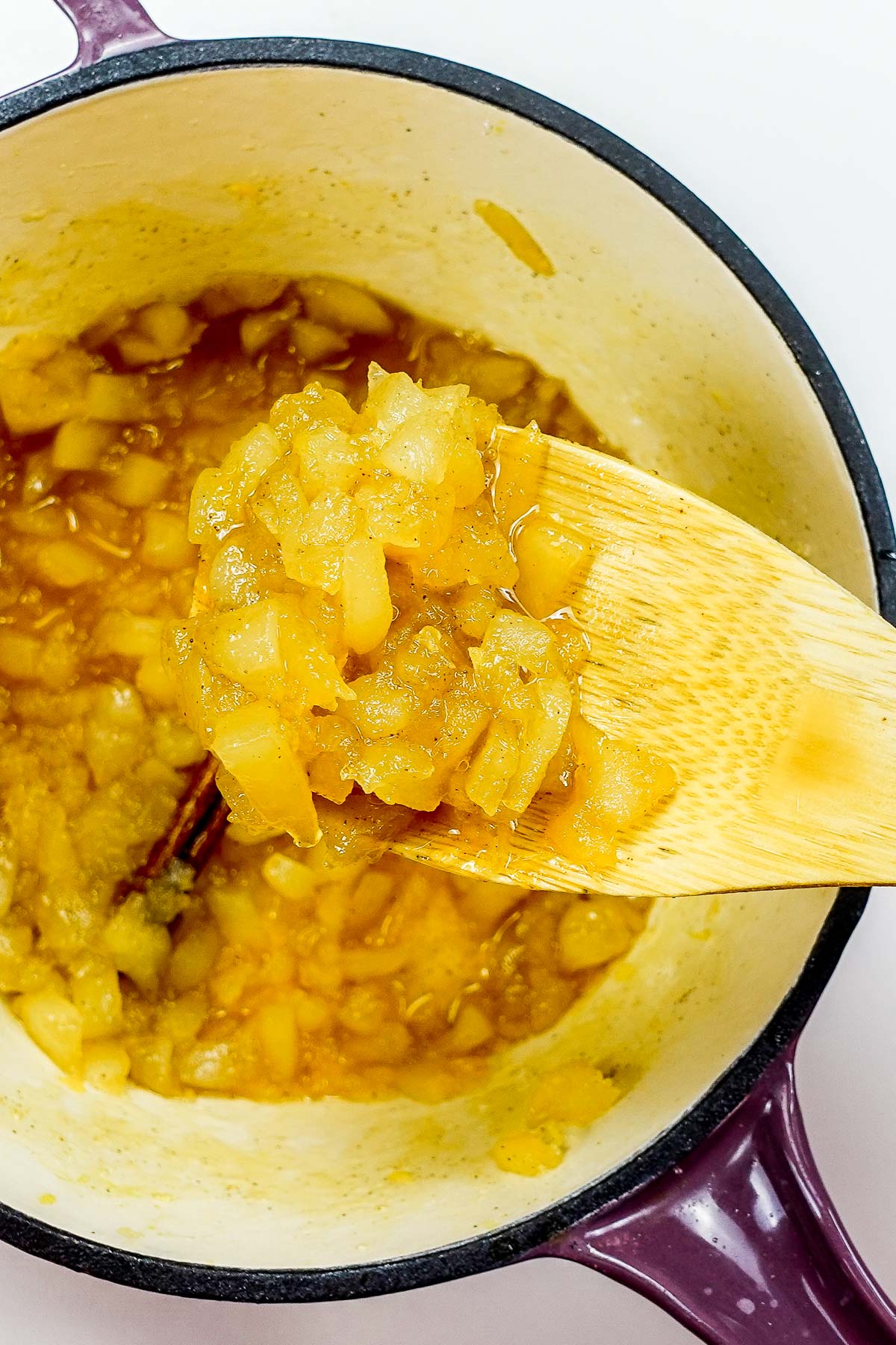 A pot with pear jam and a big spoon on top of the violet pot