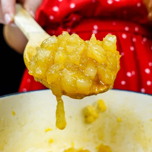 Helena is holding a spoon with a ready golden pear jam over the pot
