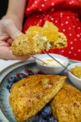 Helena is holding one scone with pear jam on top.