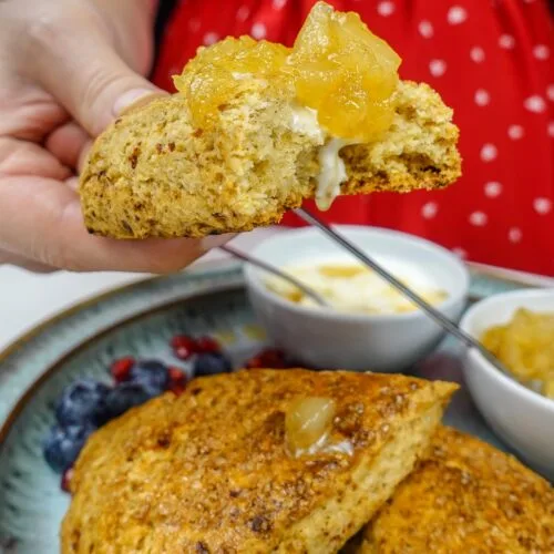 Helena is holding one scone with pear jam on top.
