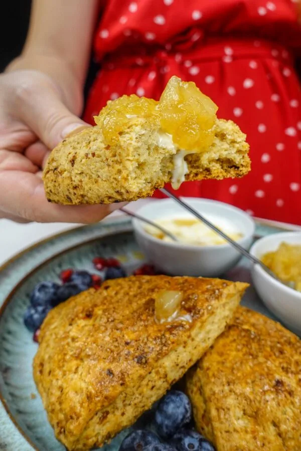 Helena is holding one scone with pear jam on top.