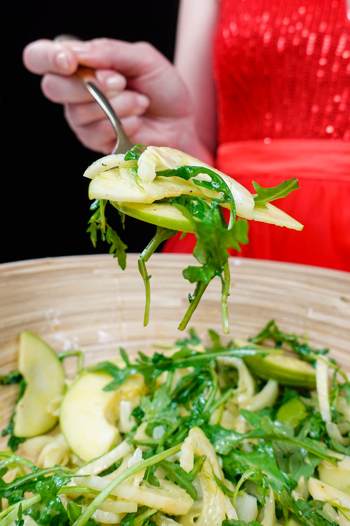Helena is holding a fork full of fresh and juicy fennel apple salad