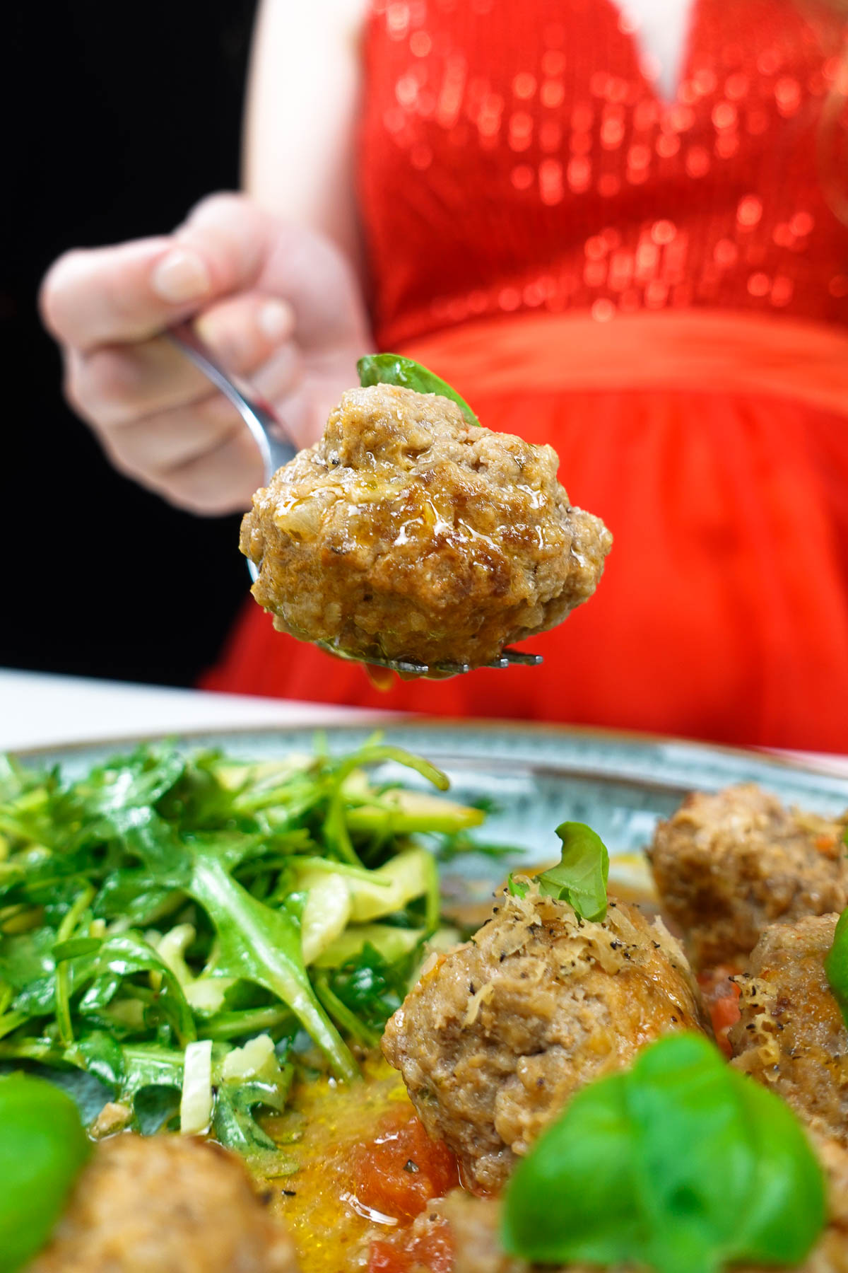 A plate with delicious meatballs with black truffle mushroom and Helena is holding one meatball with black truffle on a fork