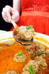 Helena is holding a wooden spoon with meatball over the skillet with meatballs