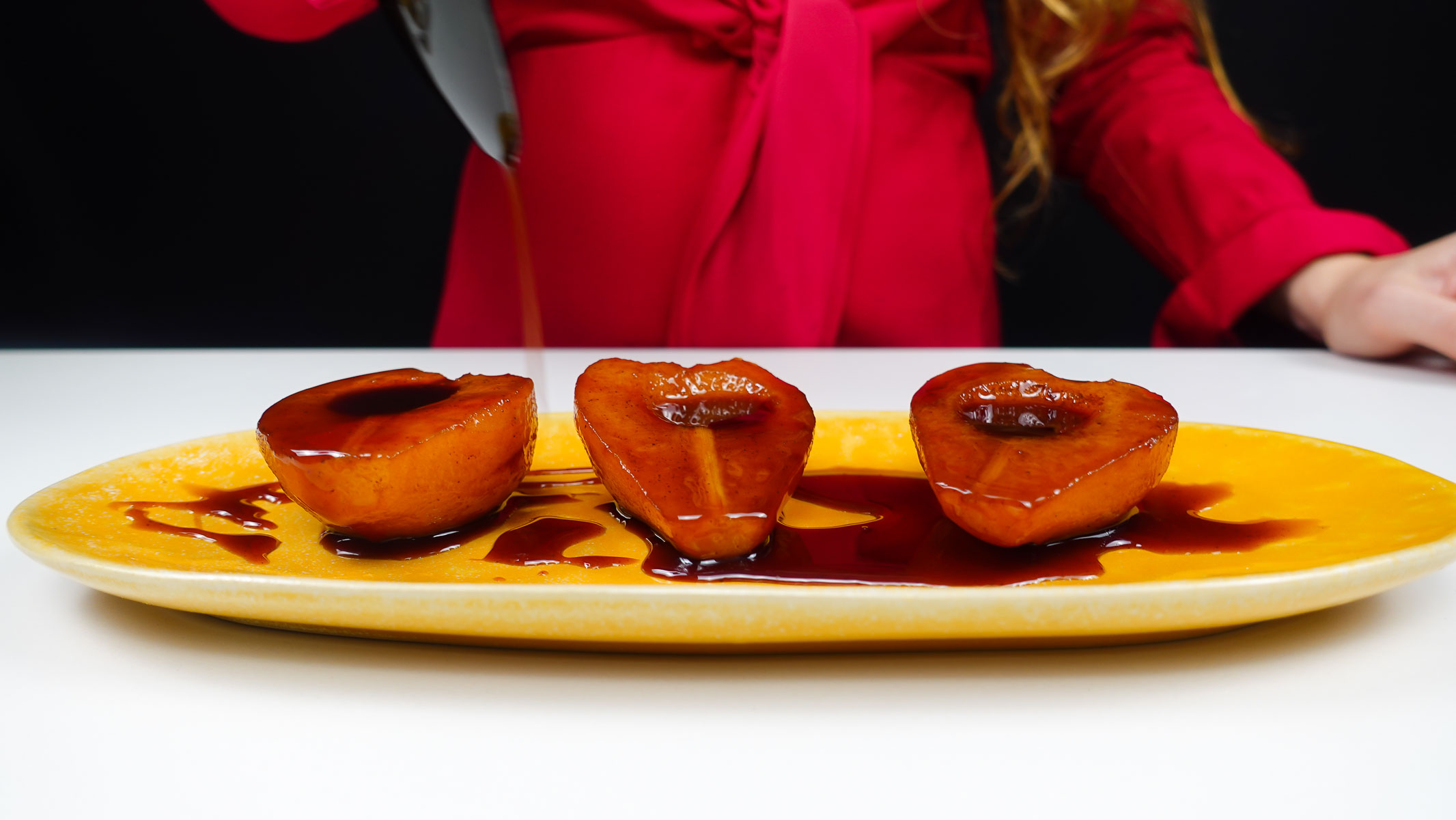 Helena is pouring the syrup on top of the Port Wine Poached Pears.