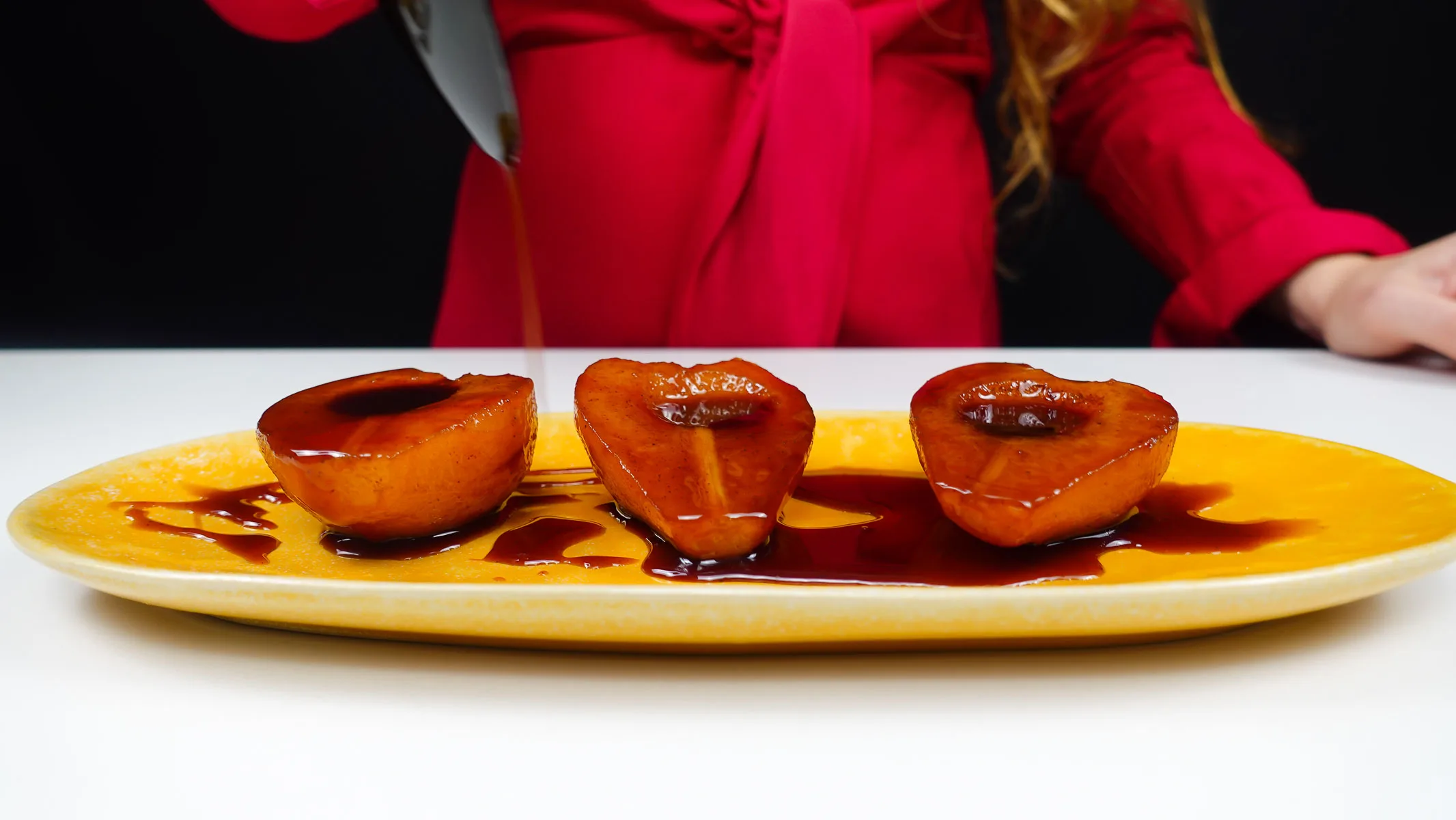 Helena is pouring the syrup on top of the Port Wine Poached Pears.