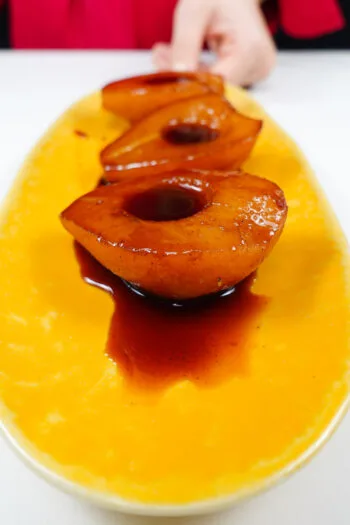 Port Wine Poached Pears with syrup on a yellow plate.