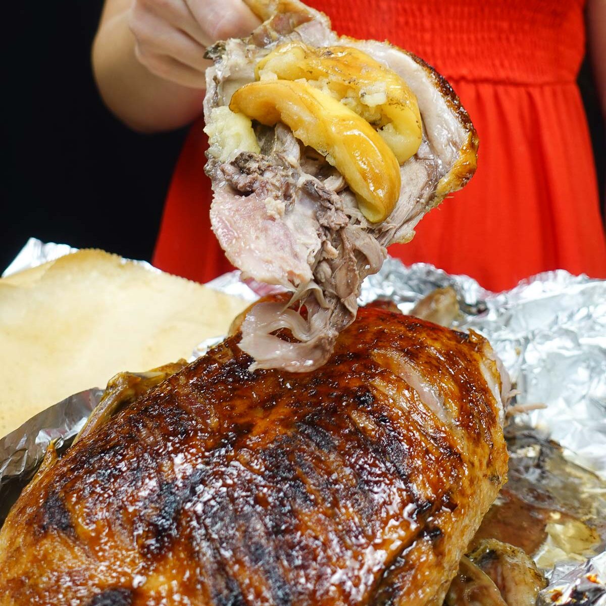Helena holding a piece of roast duck with crispy skin and stuffing.