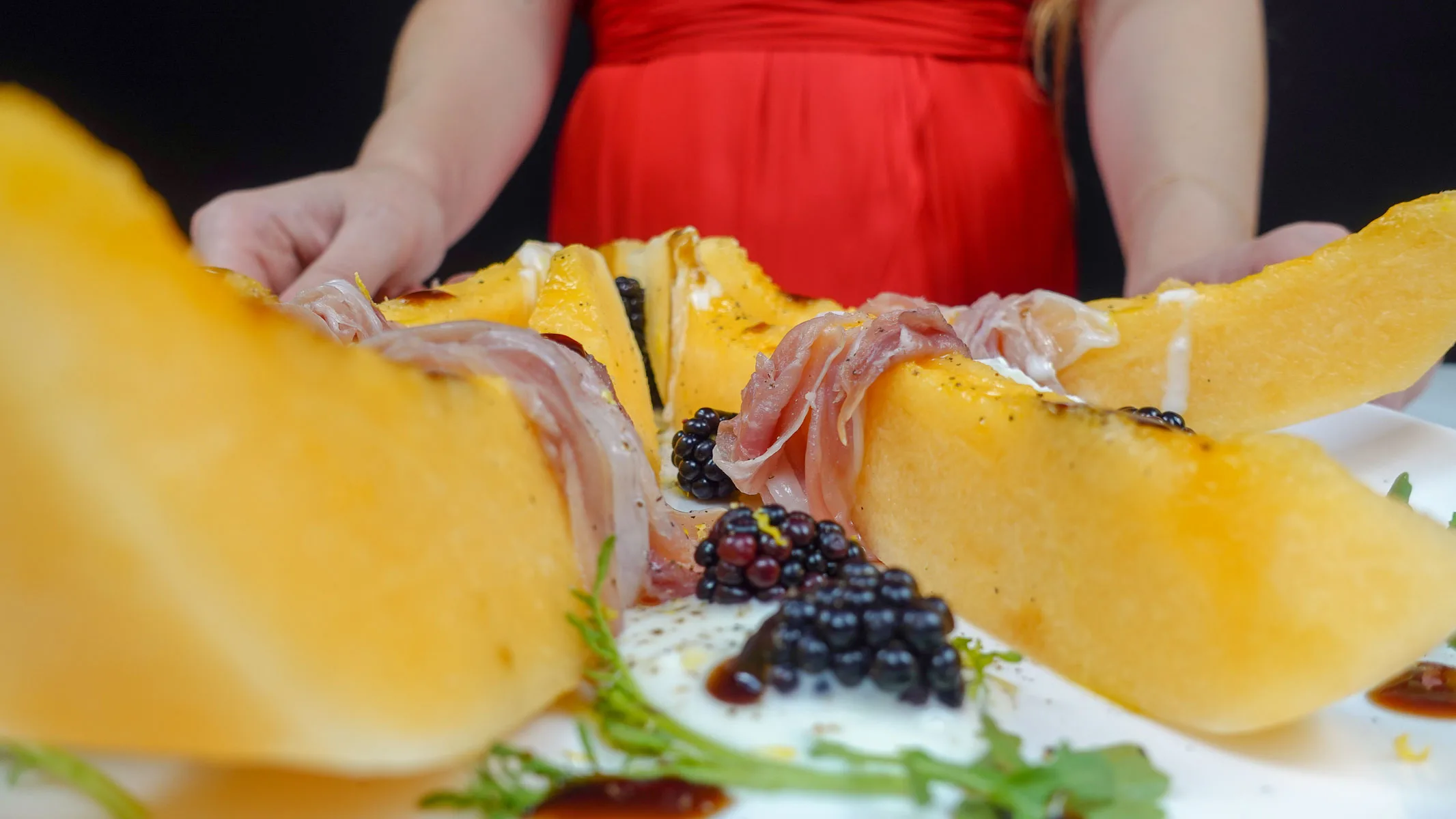 Helena is standing behind the plate with Melon Prosciutto Burrata Salad
