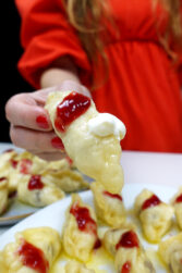 Helena is holding a cherry dumpling over the plate with delicious cherry dumplings