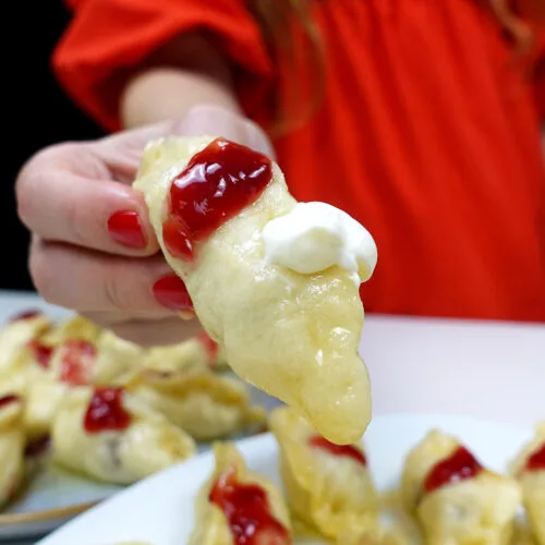 Helena is holding a cherry dumpling over the plate with delicious cherry dumplings