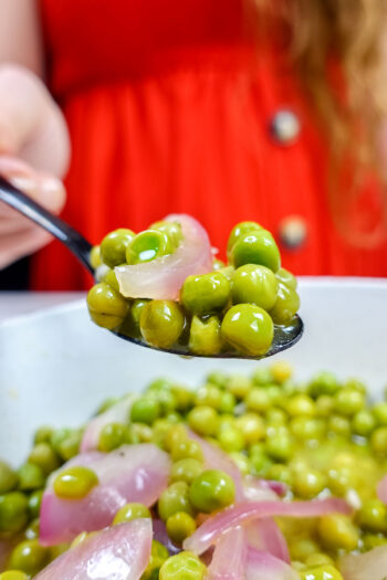 Helena is holding a spoon of green peas
