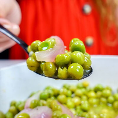 Helena is holding a spoon of green peas