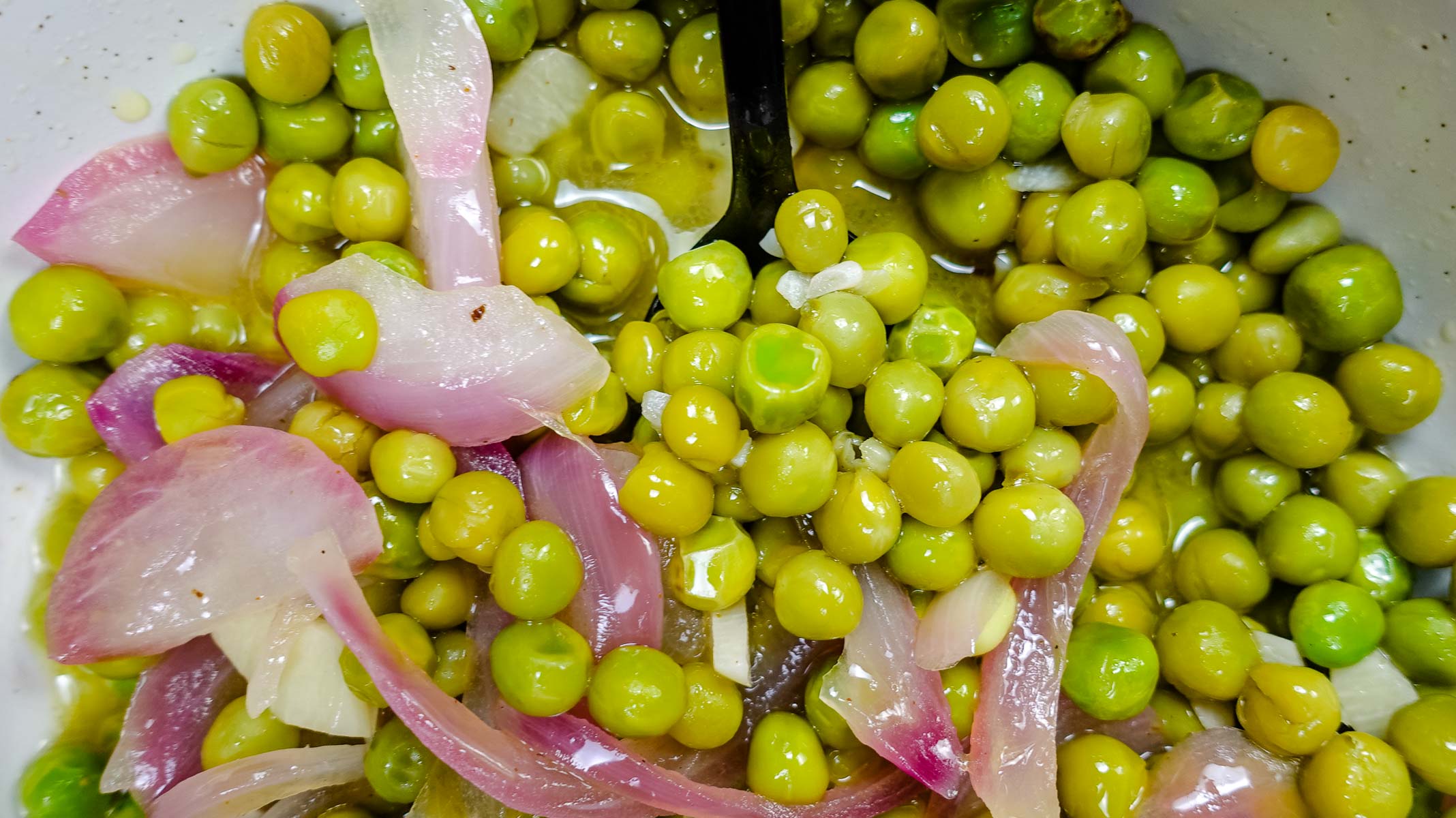Delicious Lemon Garlic Sauteed Peas in a bowl with spoon