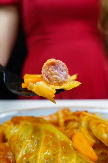 Helena is holding a fork with sausage and cabbage