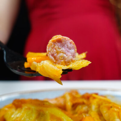 Helena is holding a fork with sausage and cabbage