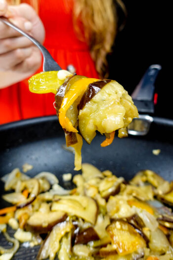 Helena is holding vegetables over the pot with sauteed vegetables