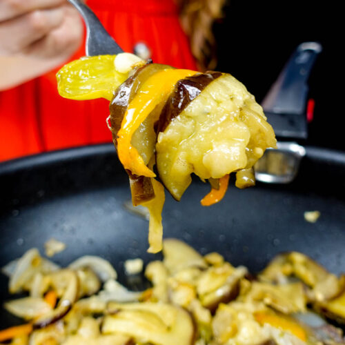 Helena is holding vegetables over the pot with sauteed vegetables
