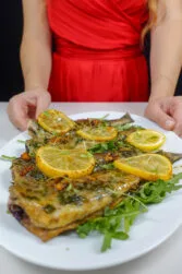 Helena is holding a white plate with mouthwatering Trout in Lemon Garlic Sauce