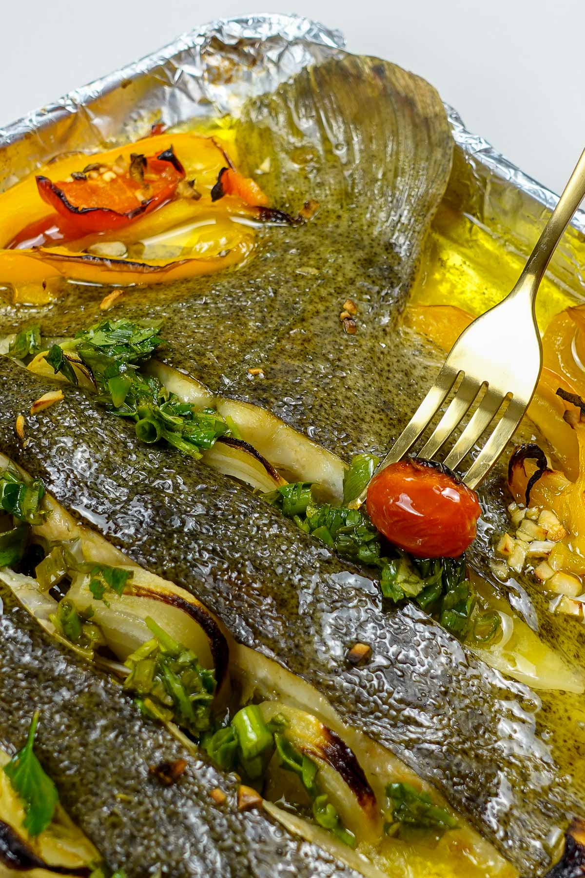 Oven baked turbot on a tray with a fork.