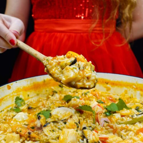 Helena is standing behind and holding a spoon with seafood rice