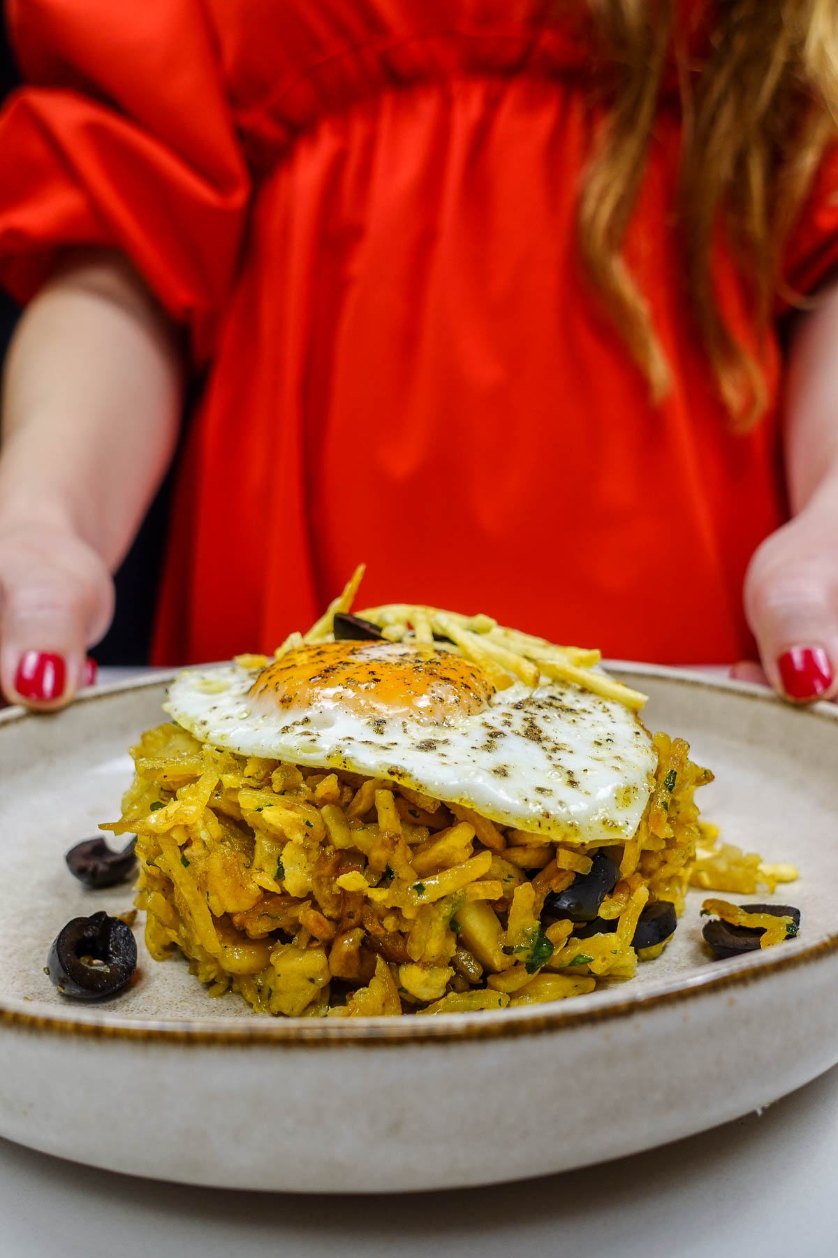 Helena is holding a plate of salt cod with potatoes and eggs