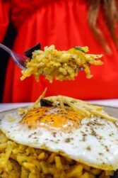 Helena is holding a fork full of cod with potatoes over the plate with bacalhau a bras