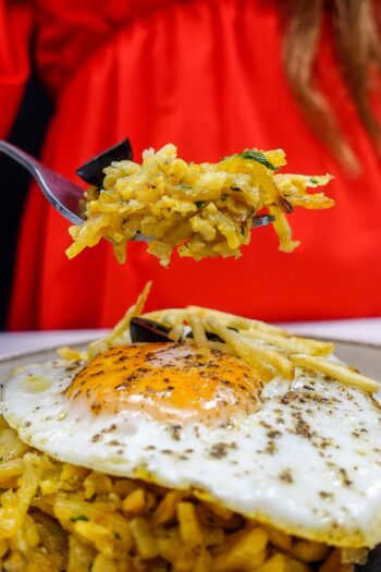 Helena is holding a fork full of cod with potatoes over the plate with bacalhau a bras