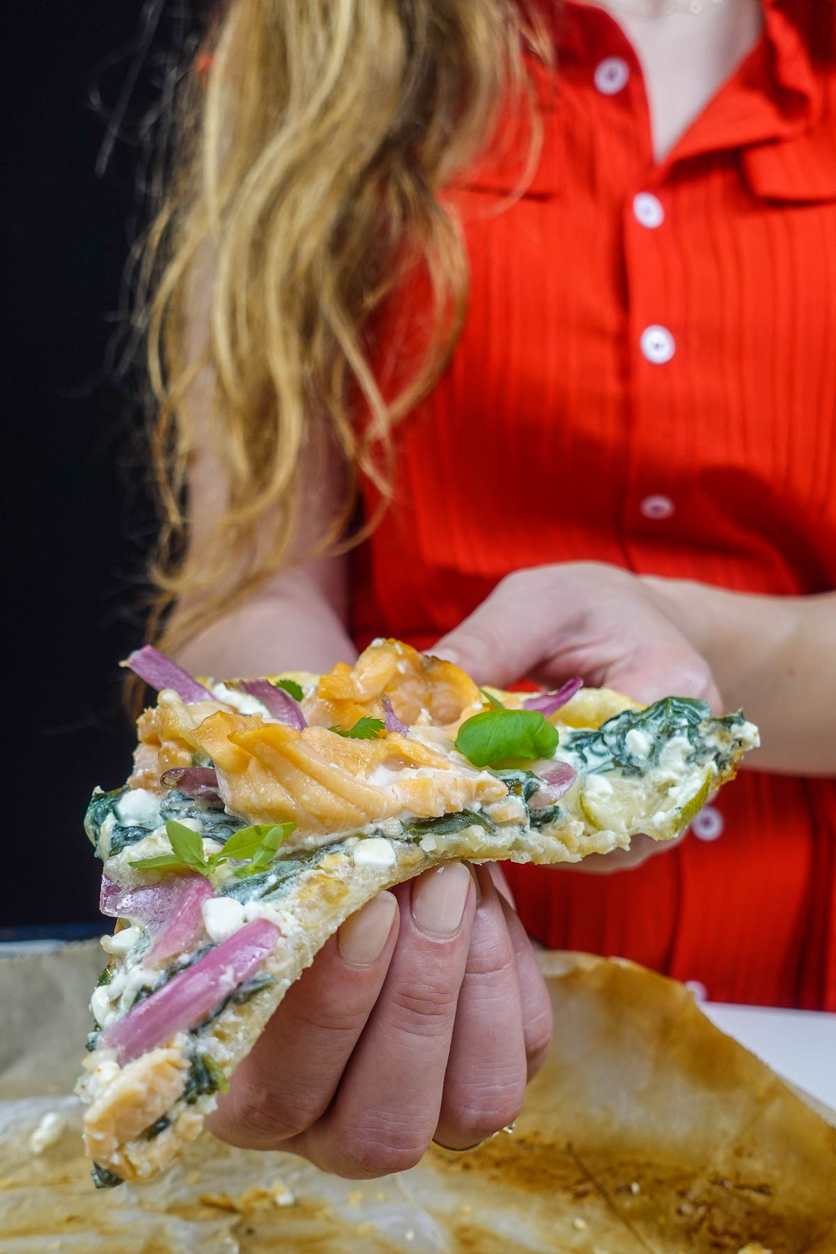 Helena is holding a delicious piece of smoked salmon tart with cottage cheese over the tray