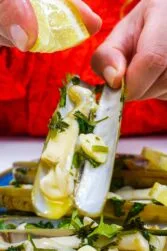 Helena is holding a beautifully cooked razor clam in left hand and drizzling lemon juice on top
