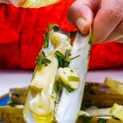 Helena is holding a beautifully cooked razor clam in left hand and drizzling lemon juice on top