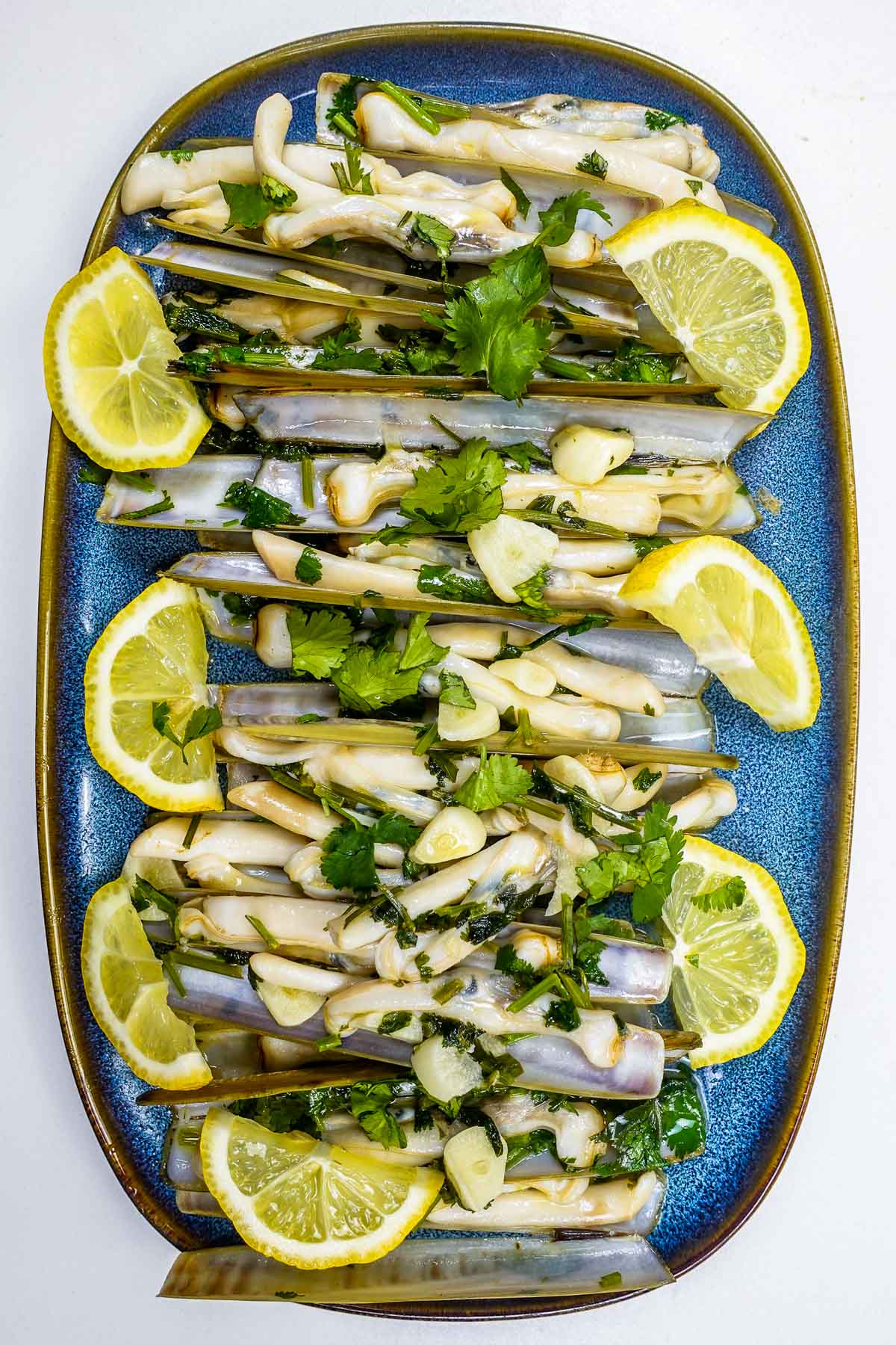 A blue plate with Portuguese razor clams in wine sauce