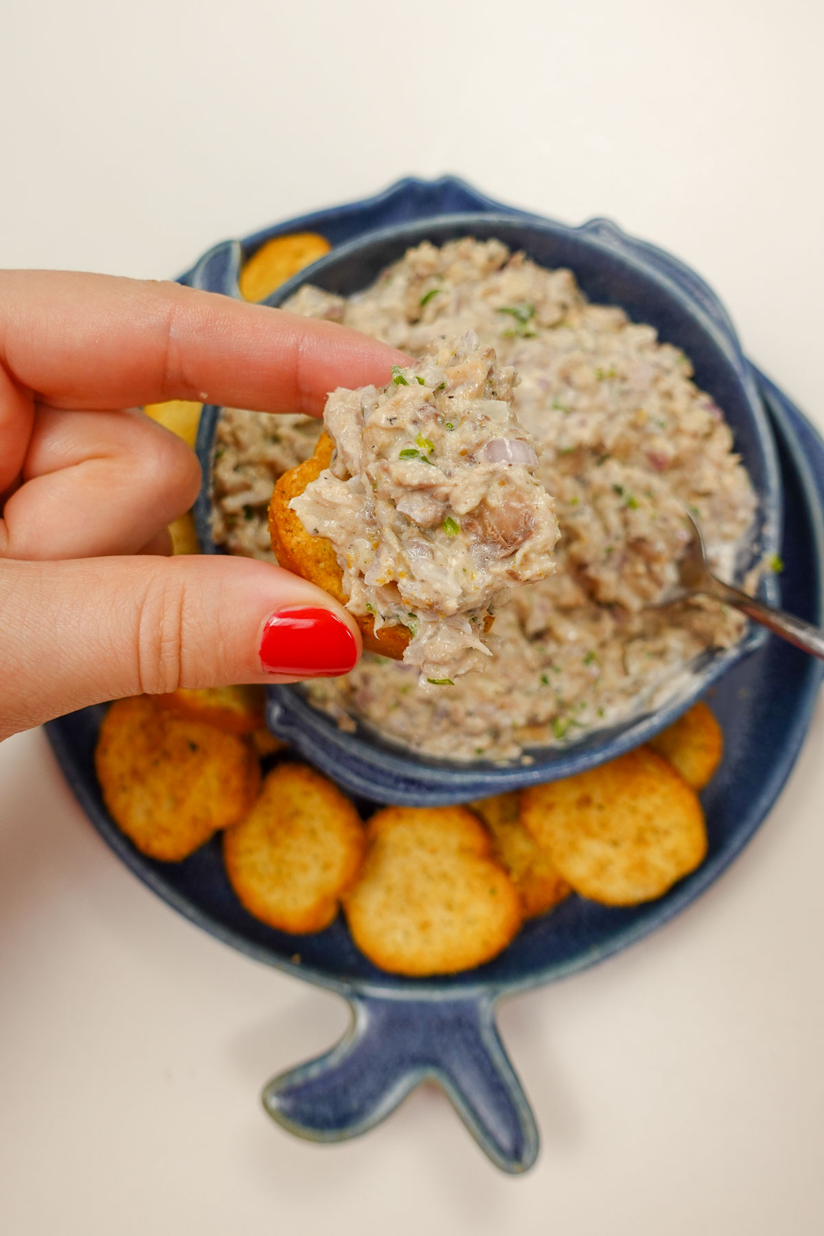 Helena is holding a piece of crackers with Portuguese sardine pate on top