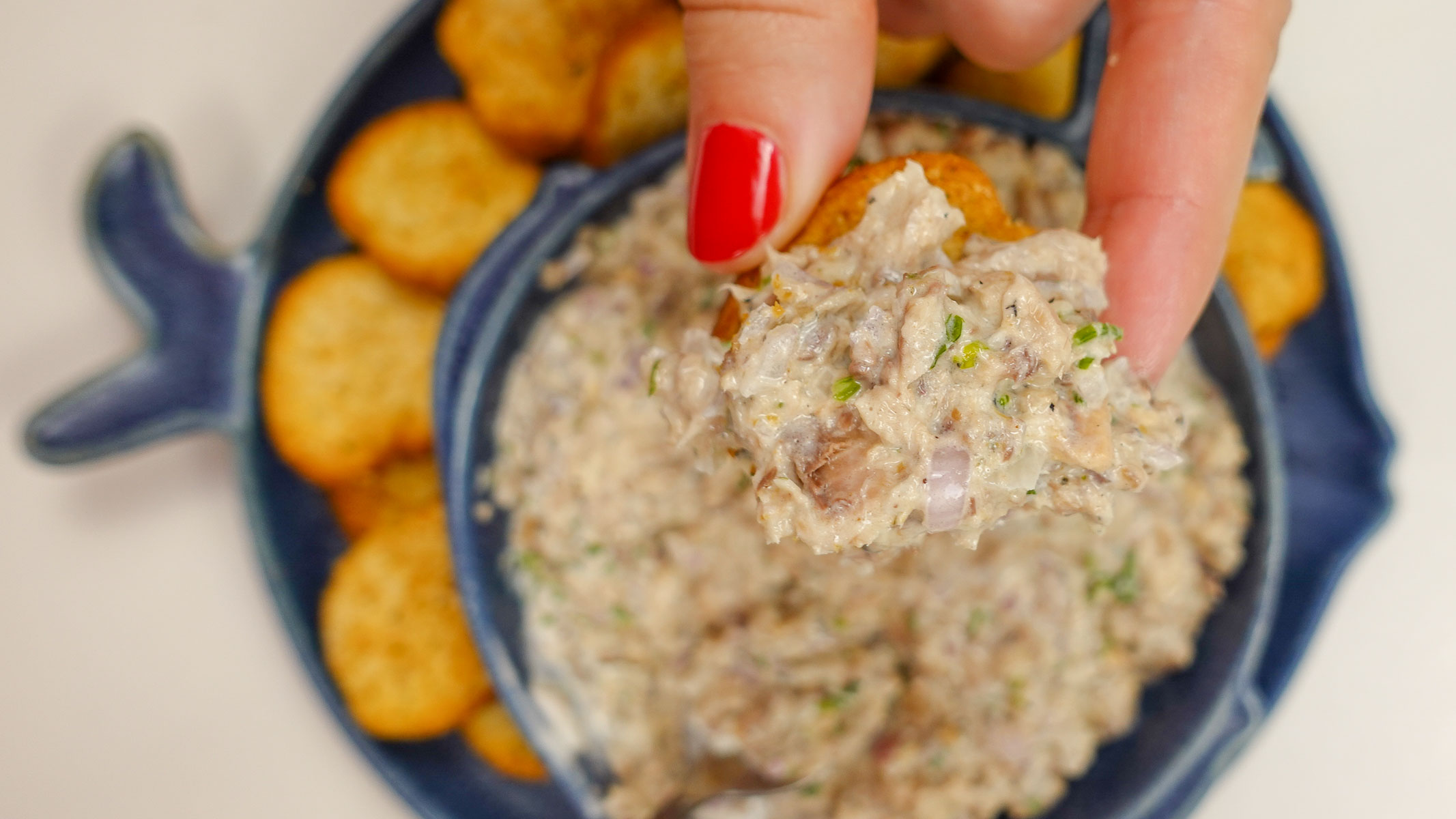 Helena is holding a cracker with sardine pate over bowl