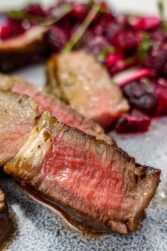 A closeup of juicy steak on a plate.