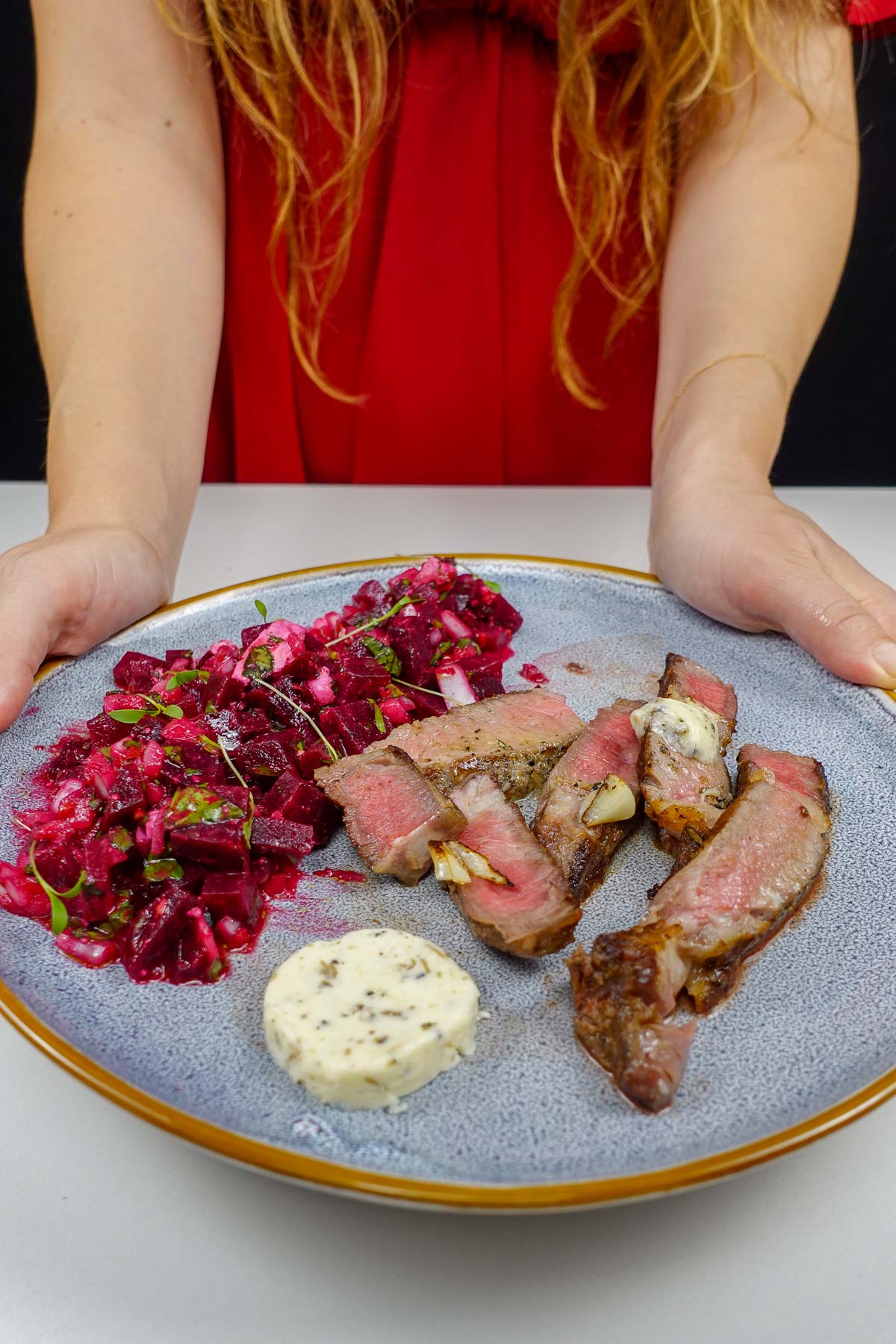 Steak with Black Truffle Butter on a plate in Helena's hands.