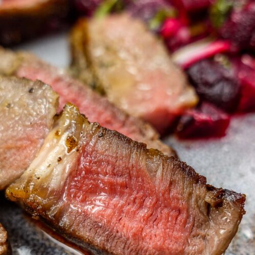 A closeup of juicy steak on a plate.