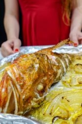 Helena is holding a tray of ready baked Mediterranean Scorpionfish with onions and lemon.