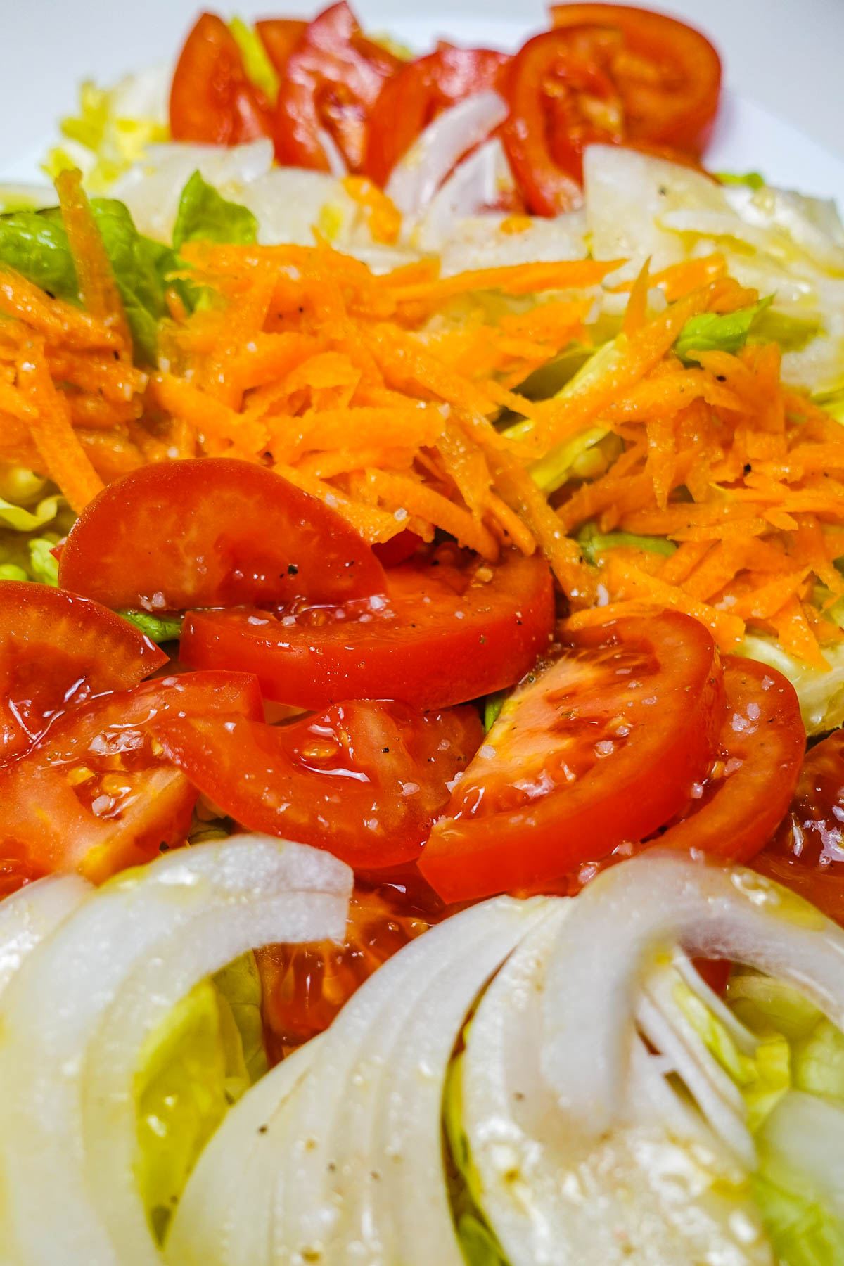A plate of freshly made Portuguese mixed salad with gross salt on top of vegetables.